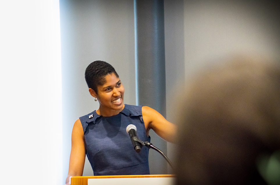 The presenter smiles while speaking to her audience.