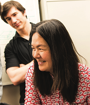 Evelyn Wang smiles while working with graduate students.