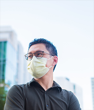 Gene-Wei Li stands in front of the skyline, wearing a surgical face mask.