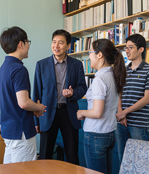 Harry Lee talks with a group of graduate students, all smiling.