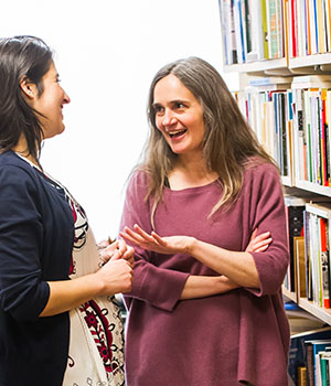 Heather Paxson talks with a graduate student in a library, smiling.