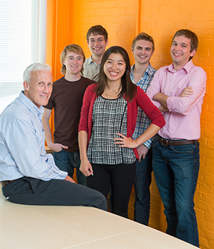 Kord Smith and a group of graduate students pose in a colorful classroom.