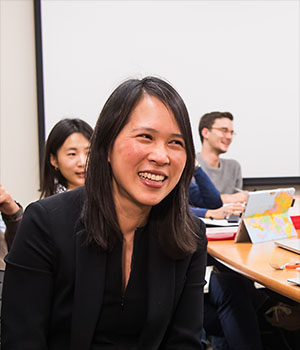 Lily Tsai laughs with a group of graduate students while they work.
