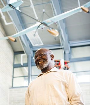 Wesley Harris smiles, an airplane visible hanging from the ceiling behind him.
