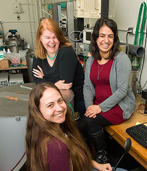 Janet Conrad and two graduate students laugh together in the lab.