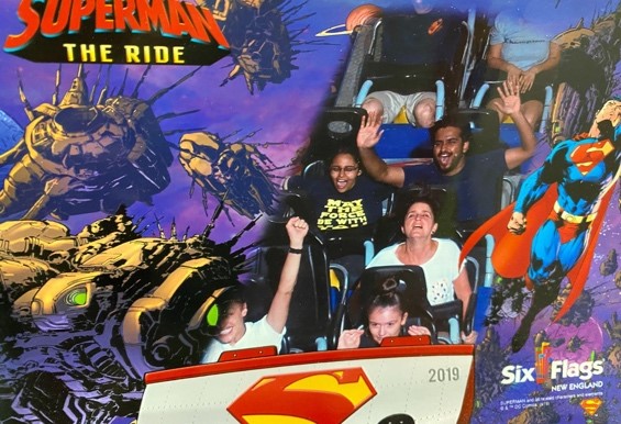A group of people, with Vyshnavi and Sharan in the center, scream with excitement on a roller coaster descent.