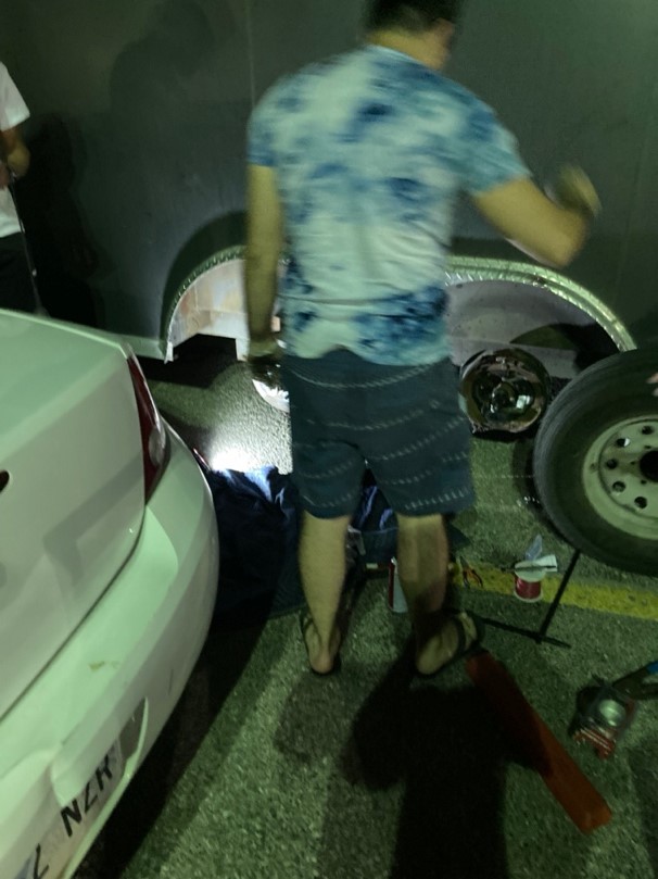 Jonathan, blurred by motion, works on repairing the wheel in a parking lot at night.