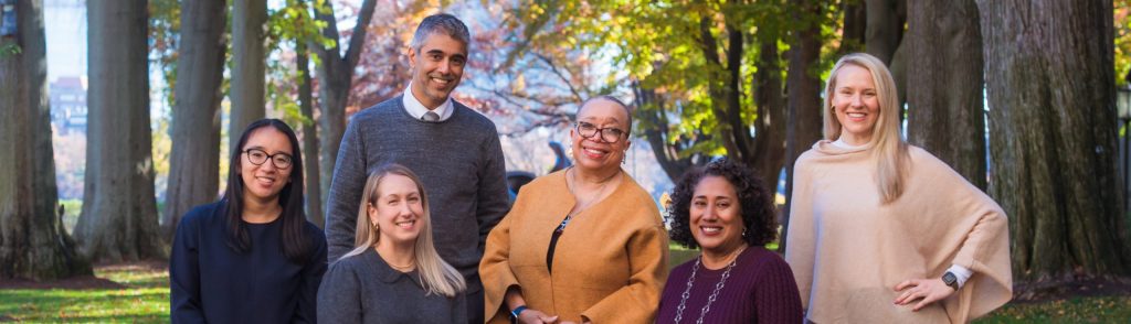 The GradSupport team stand together, smiling, on a sunny autumn day on campus.