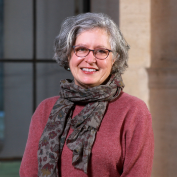 A bespectacled woman smiles at the camera