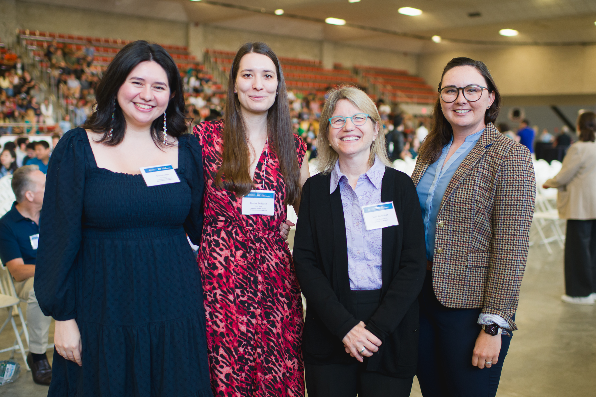 Three graduate students stand with MIT President Sally Kornbluth at an Orientation event. All are smiling.