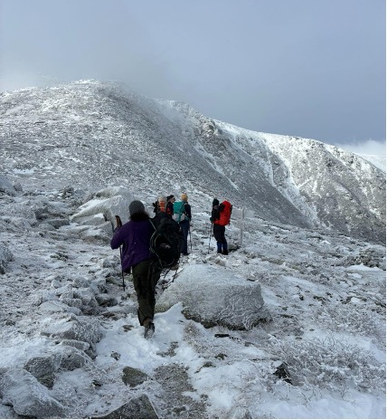 The group continues hiking ahead up a snow-covered mountain slope.