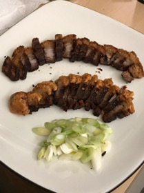 Two arcs of sliced food and a small pile of sliced green onions, plated.