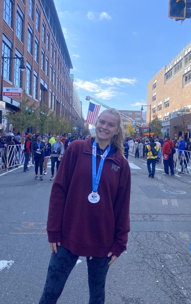 A blonde woman smiles, wearing a race medal