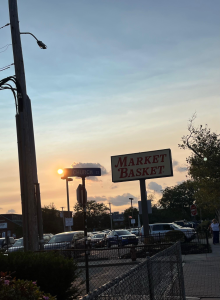 The 'Market Basket' sign is set against a sunset