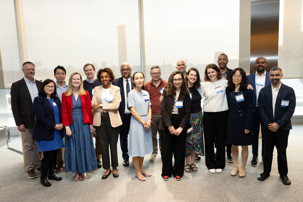17 people, including Committed to Caring faculty, pose in front of a white backdrop.