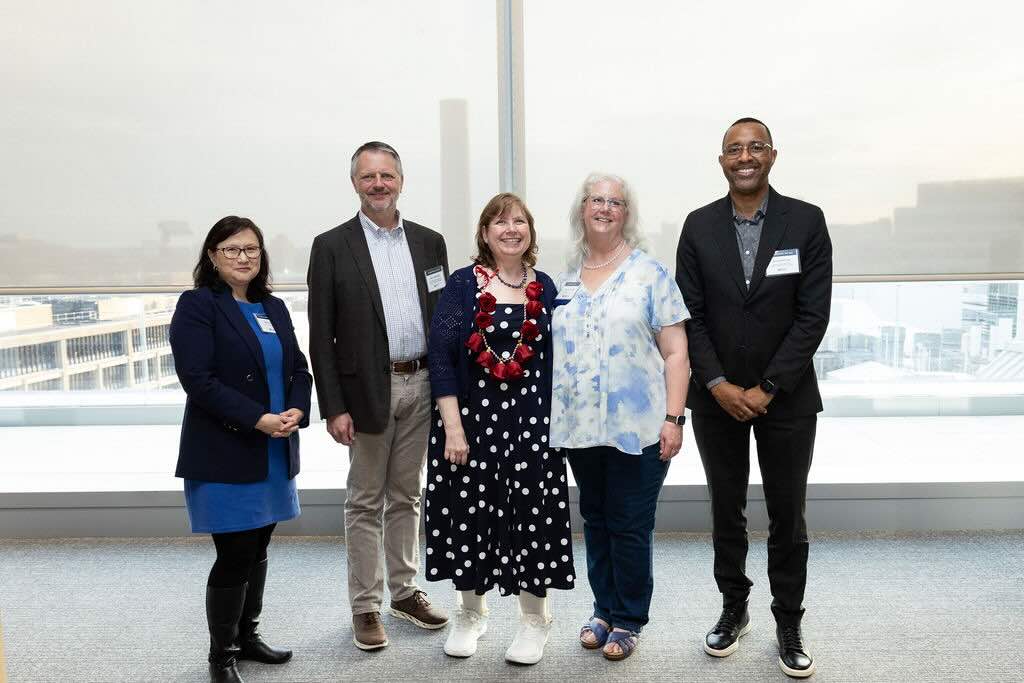 Five people, including Enduring Impact staff, pose in front of a white backdrop.