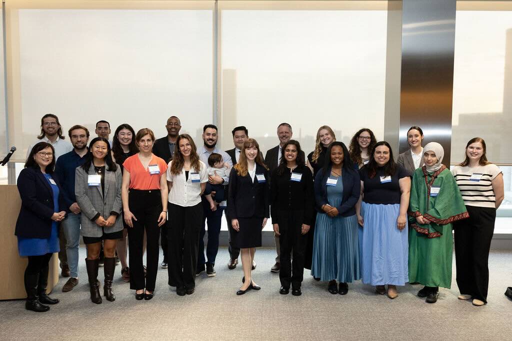 21 people, including Graduate Students of Excellence, pose in front of a white backdrop.
