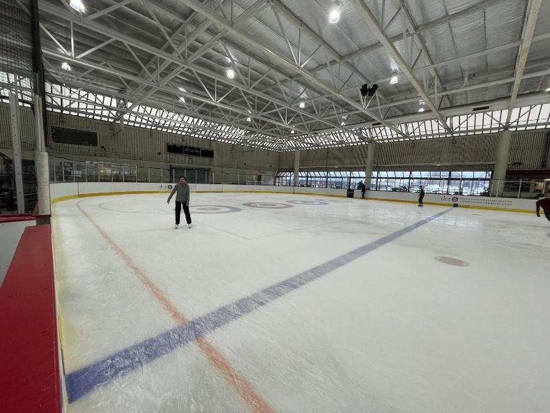 A graduate student ice skates alone on an empty indoor rink